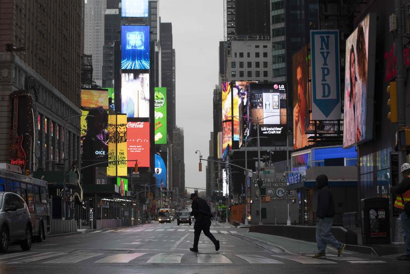 Dos hombres caminan por las calles casi desiertas de Times Square, en la Ciudad de Nueva York, el lunes por la mañana. (AP Photo/Mark Lennihan)