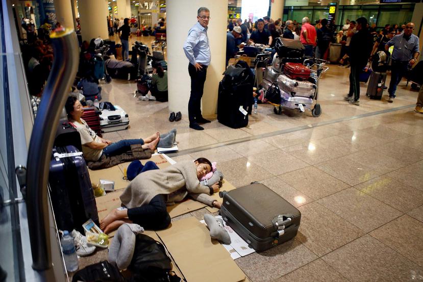 Cientos de viajeros esperan la reprogramación de sus vuelos en el aeropuerto de El Prat de Barcelona. (EFE/Quique García)