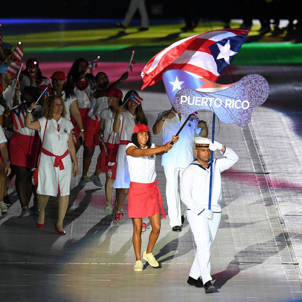 Arriba, la nadadora Vanessa García carga la bandera de Puerto Rico durante el desfile de la delegación en los pasados Juegos Centroamericanos y del Caribe de Barranquilla 2018.