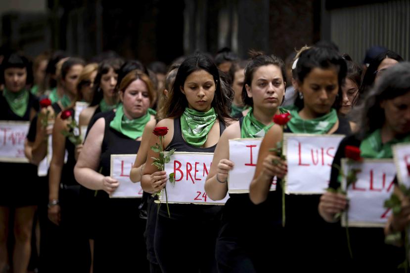 Mujeres marchandocada una con una flor y un cartel con el nombre de una mujer asesinada en 2020, durante el Día Internacional de la Mujer en Argentina. (AP)