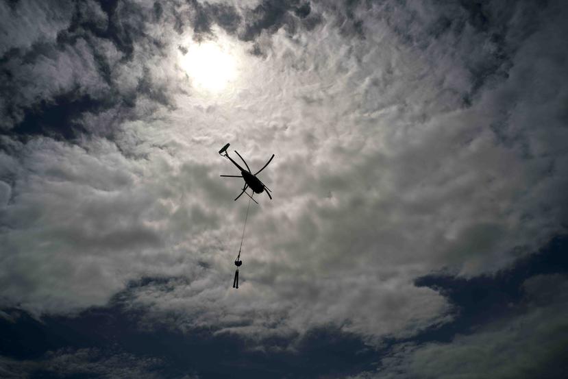 Un helicóptero de Whitefish Energy Holdings sobrevuela unas torres de líneas eléctricas en Barceloneta. (AP)