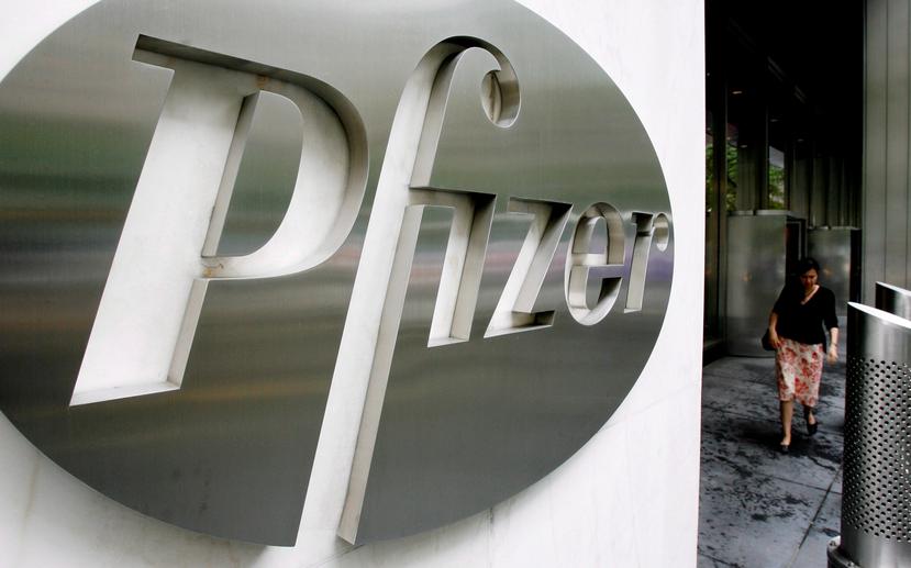 Fotografía que muestra a una persona mientras camina frente al logo de Pfizer en Nueva York.