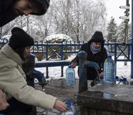 Ciudadanos recolectan agua de una toma pública que todavía funciona pese a los constantes bombardeos de Rusia a instalaciones de servicios públicos como energía y agua potable.