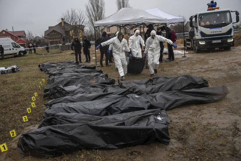 Trabajadores forenses cargan el cadáver de un civil asesinado durante la guerra contra Rusia después de recogerlo de una fosa común en Kiev, Ucrania.