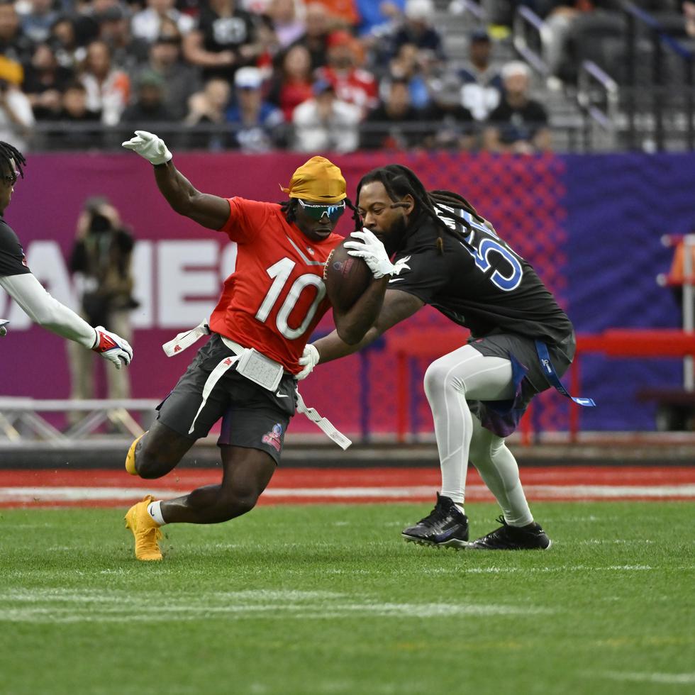 El wide receiver Tyreek Hill (10) acarrea el balón ante la marca del cornerback Tariq Woolen (27) y linebacker Za'Darius Smith (55) durante un juego de fútbol bandera durante el Pro Bowl de la NFL, el 5 de febrero de 2023, en Las Vegas.