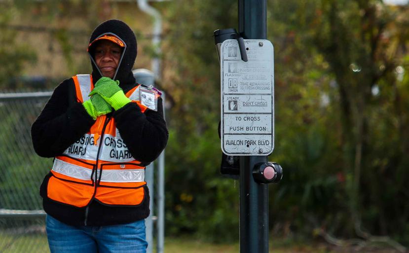 Una guardia de cruce de peatones se abriga por el frío que impacta Florida.