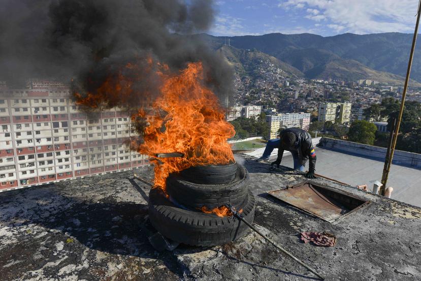 Neumáticos encendidos por milicias progubernamentales arden en lo alto de un edificio de apartamentos durante un ejercicio militar en el barrio 23 de Enero, Caracas, Venezuela, sábado 15 de febrero de 2010. (AP/Matias Delacroix)