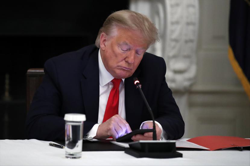 Fotografía de archivo del 18 de junio de 2020 del presidente Donald Trump usando su teléfono durante una reunión con gobernadores en la Casa Blanca, en Washington.