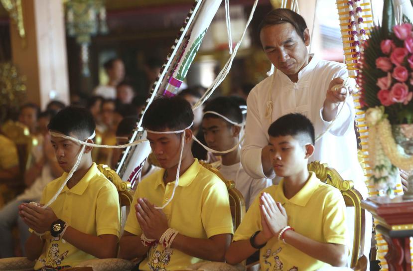 El entrenador Ekkapol Janthawong (centro) y niños del equipo de fútbol rescatado de una cueva anegada durante una ceremonia budista. (AP)