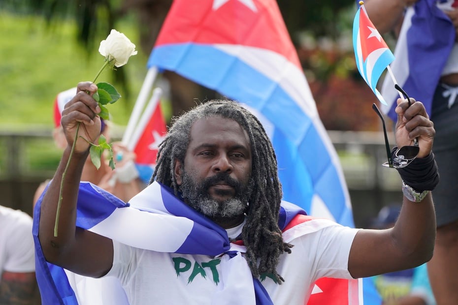 A protester holds a white rose and a Cuban flag as he joins those gathered to support the protests in Cuba.