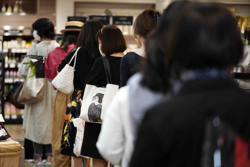 Clientes manteniendo distancia entre ellas mientras esperan en fila para pagar en una sección de alimentación de los grandes almacenes Matsuya Ginza en Tokio.