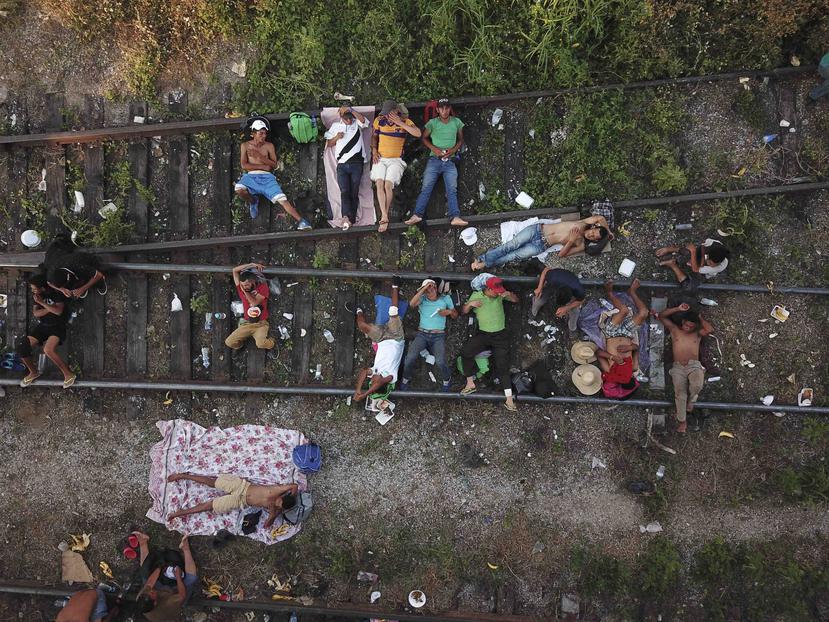 Migrantes que forman parte de una caravana de centroamericanos que avanza lentamente hacia la frontera con Estados Unidos, descansa sobre las vías del tren en Arriaga, México, el 26 de octubre de 2018. (AP/Rodrigo Abd)