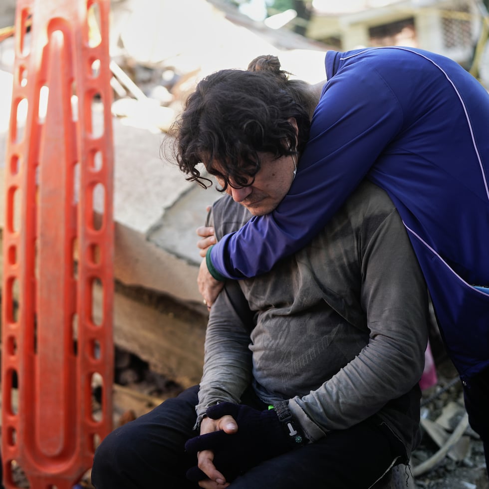 Vecinos se abrazan mientras los rescatistas buscan entre los escombros de su edificio de apartamentos derrumbado, un día después del terremoto que azotó Cali, Colombia, el martes 11 de agosto de 2026.