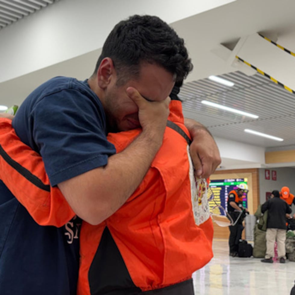 German Bello, a la derecha, voluntario de la brigada mexicana de búsqueda y rescate "Los Topos Azteca", abraza a un venezolano que se acercó al equipo para darles las gracias mientras partían hacia Venezuela desde el aeropuerto de Ciudad de México.