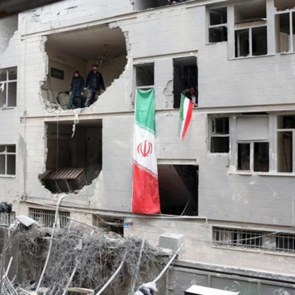 Iraníes se encuentran dentro de su edificio residencial dañado en el sur de Teherán.