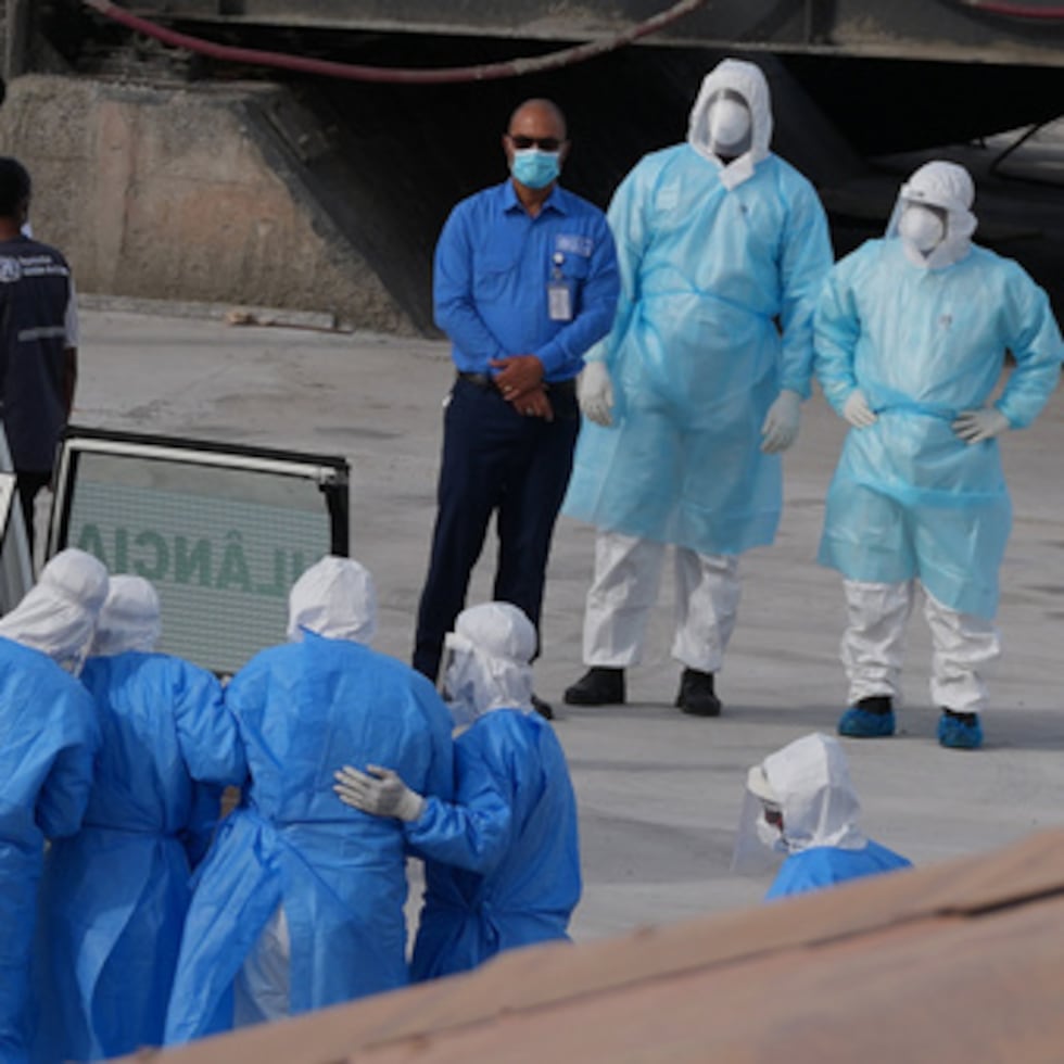 Trabajadores sanitarios con equipos de protección evacúan a pacientes del crucero MV Hondius a una ambulancia en un puerto de Praia, Cabo Verde.