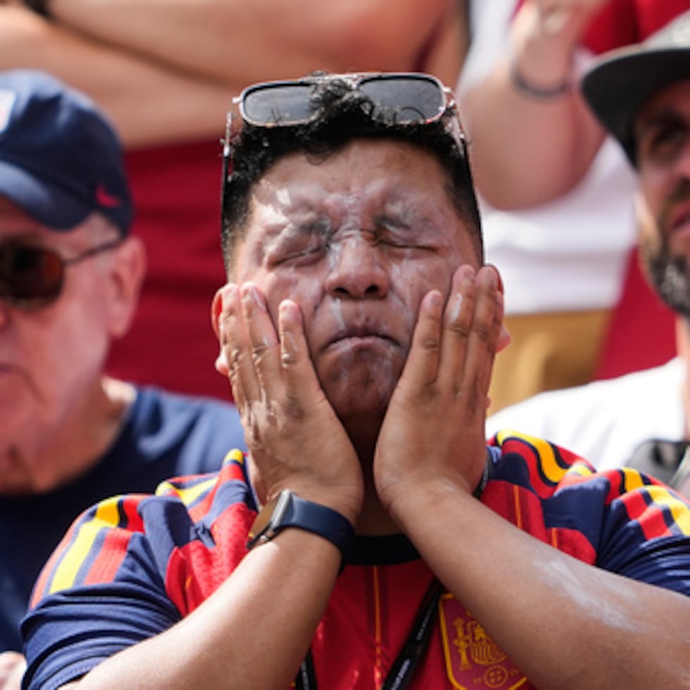 Un aficionado se pone crema solar antes del partido de un fútbol.