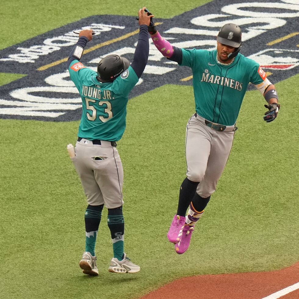 Julio Rodríguez, de los Mariners (derecha), celebra con el coach de primera base Eric Young Jr. (53) mientras recorre las bases tras conectar un jonrón de tres carreras contra los Blue Jays durante la primera entrada del Juego 2 de la Serie Divisional de la Liga Americana.