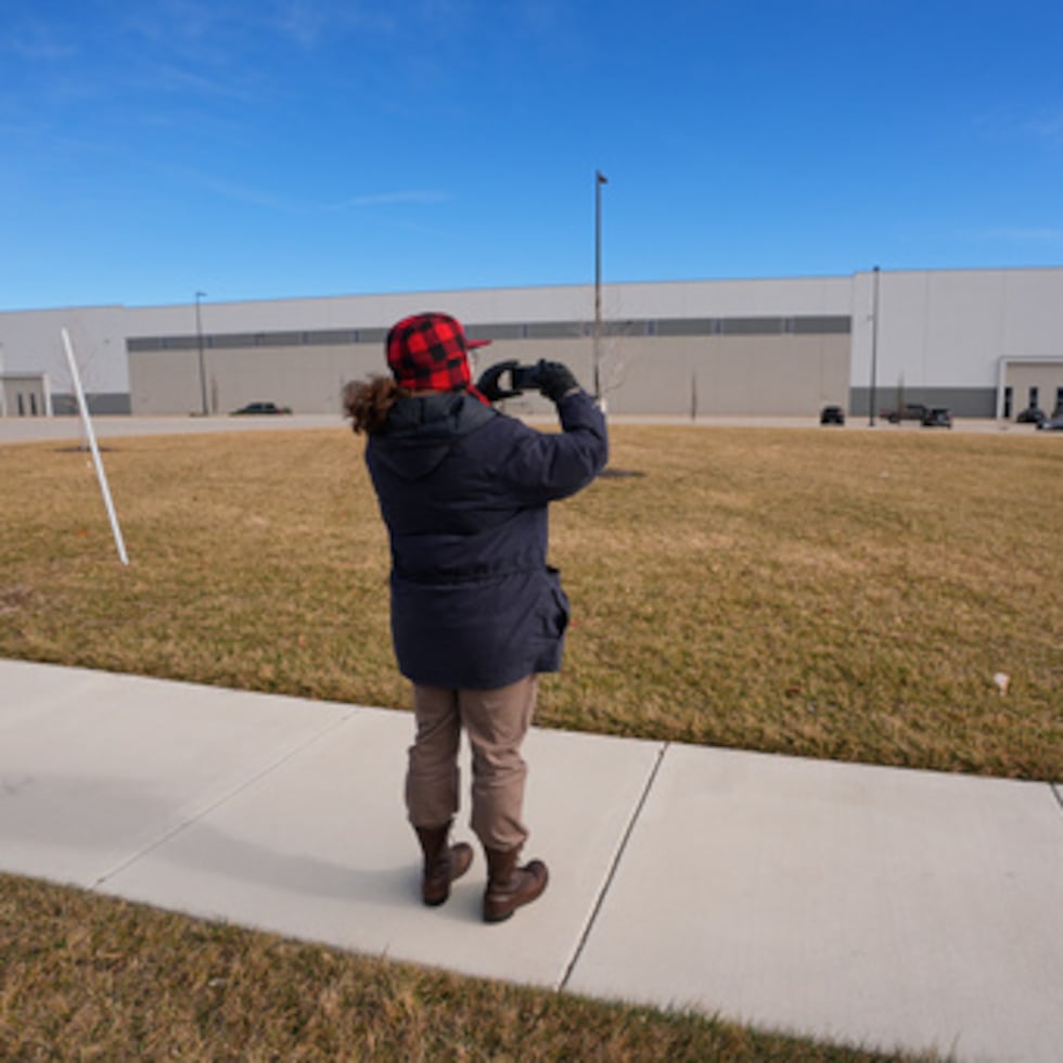 Un hombre toma fotos de un almacén mientras funcionarios federales recorren las instalaciones para considerar su reutilización como centro de detención del ICE, en Belton, Missouri.