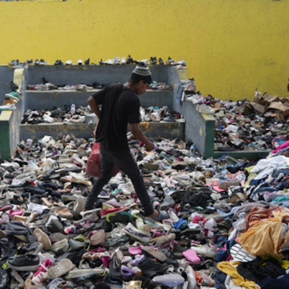 Una persona elige entre la ropa donada a los damnificados por los terremotos en un complejo deportivo, el sábado 4 de julio de 2026, en La Guaira, Venezuela.