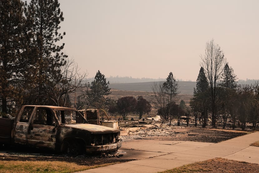 Un camión calcinado permanece en la entrada de una casa cerca de varias viviendas destruidas en un barrio residencial el martes 4 de agosto de 2026, tras un incendio forestal que azotó la zona norte de Spokane, Washington. (Foto AP/Lindsey Wasson)
