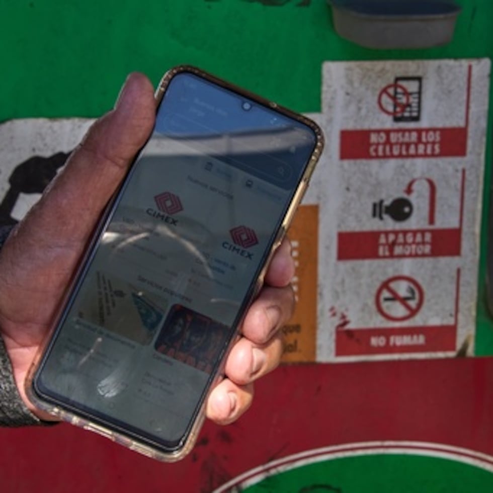 El jubilado Jorge Reyes muestra su teléfono con la aplicación "El Ticket" que se utiliza para reservar un lugar en la fila para comprar gasolina racionada en La Habana.