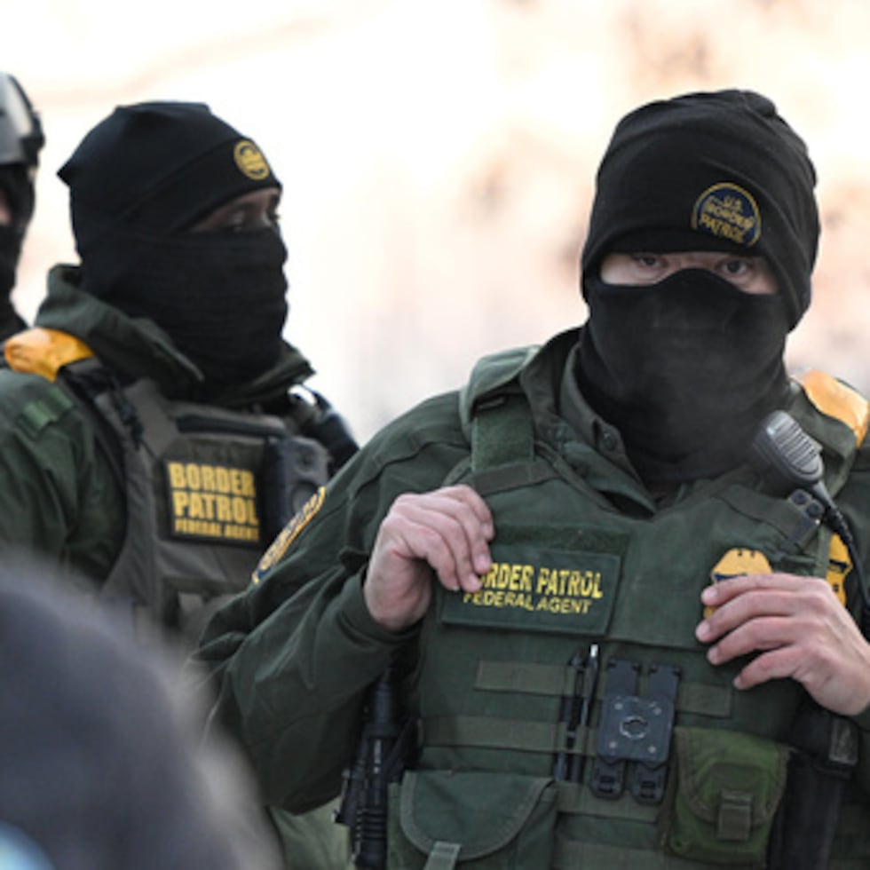 Agentes federales miran mientras los manifestantes se reúnen fuera del edificio federal Obispo Henry Whipple en Minneapolis.