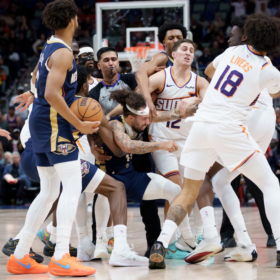 Jugadores de ambos equipos intentan separar al par de canasteros.