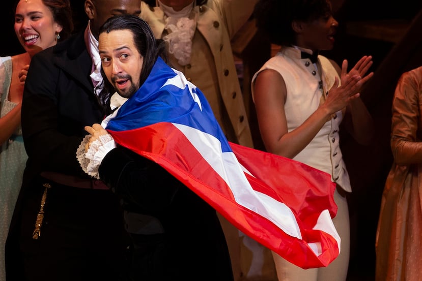 Lin-Manuel Miranda con la bandera de Puerto Rico sobre sus espaldas.