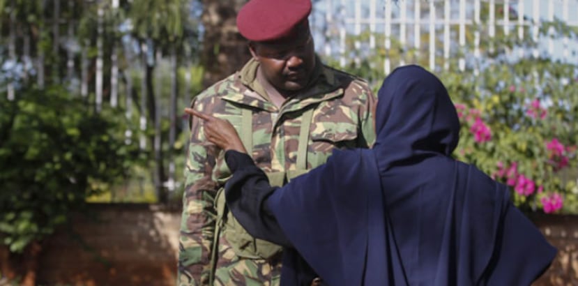 Un paramilitar keniata conversa con familiares de las personas que han sido detenenidas en un punto de control establecido a la entrada del estadio de Kasarani, Nairobi, Kenia. (EFE)