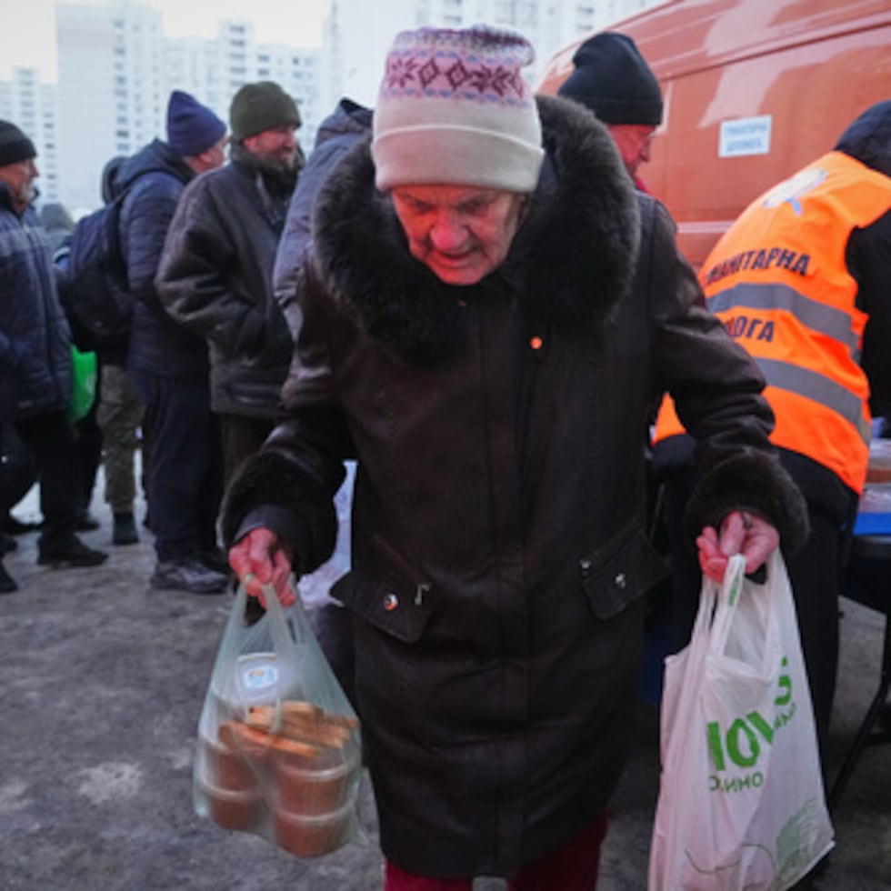 Una anciana saca sus bolsas de un punto de distribución de comida caliente durante un apagón causado por los repetidos ataques aéreos de Rusia contra la red eléctrica del país, en Kiev, Ucrania, el lunes 2 de febrero.