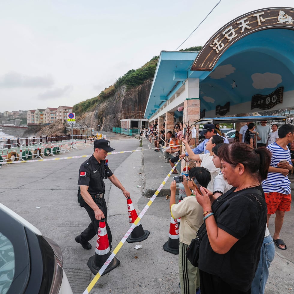 En esta fotografía difundida por la agencia de noticias Xinhua, un agente de seguridad acordona la zona costera ante la inminente llegada del tifón Bavi.