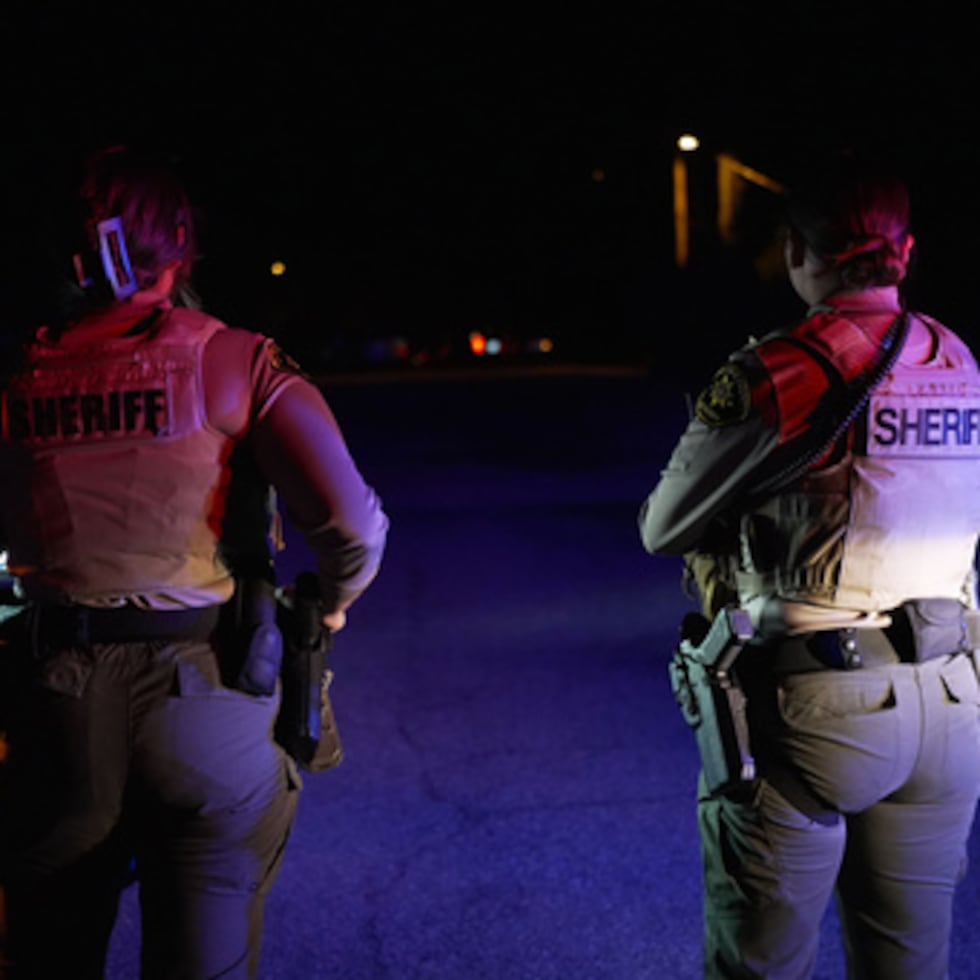 Oficiales del Sheriff bloquean la entrada a una carretera donde se estaba registrando una casa en Río Rico, Arizona.