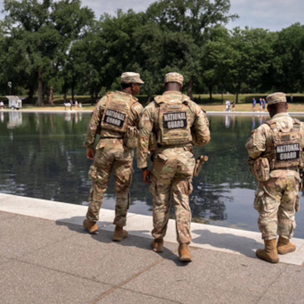 Miembros de la Guardia Nacional contemplan el estanque reflectante del Monumento a Lincoln.