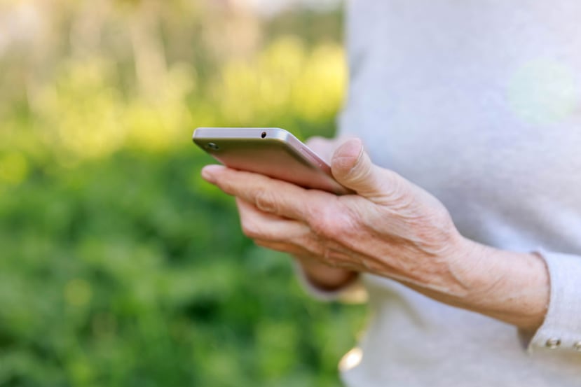 Adulta mayor sosteniendo un teléfono móvil.