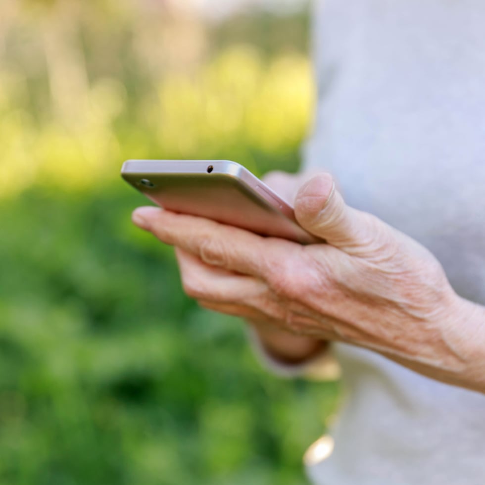 Adulta mayor sosteniendo un teléfono móvil.