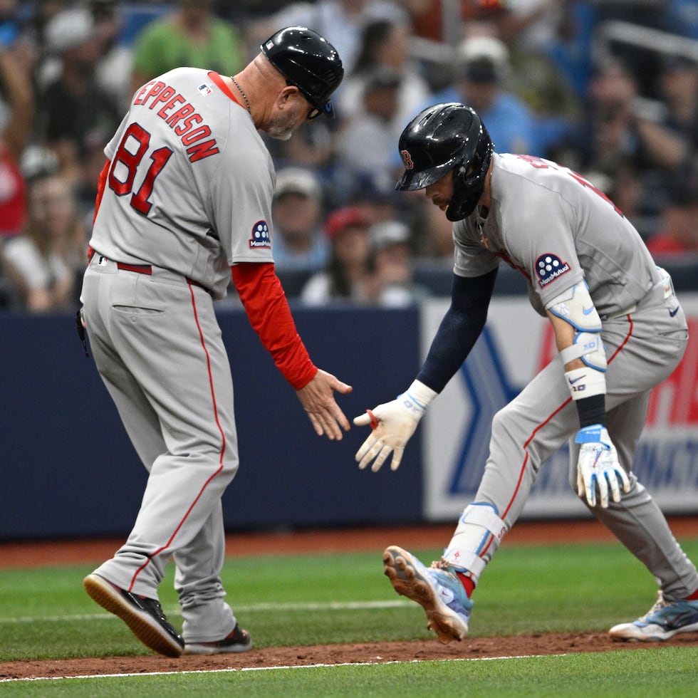 Trevor Story, de los Red Soxde Boston, es felicitado por el coach de tercera base Chad Epperson (81) después de conectar un jonrón solitario durante la novena entrada del partido contra los Rays de Tampa Bay.