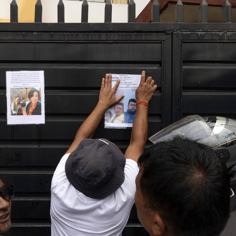 Personas pegan fotos de desaparecidos en la riada de Nepal.