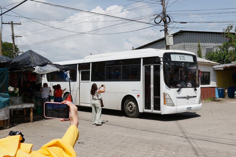 Periodistas toman fotografías de un autobús que transporta migrantes deportados de Estados Unidos tras su llegada al aeropuerto Ramón Villeda Morales en San Pedro Sula, Honduras, el jueves 20 de agosto de 2026. (Foto AP/Delmer Martínez)