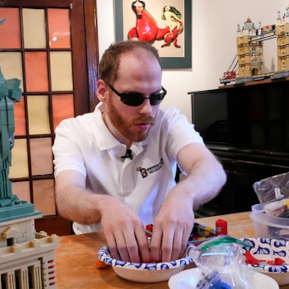 Matthew Shifrin, fundador de Bricks for the Blind, busca piezas específicas mientras construye una máquina de bolas de chicle de LEGO en casa de su familia, el viernes 20 de marzo de 2026, en Newton, Massachusetts (AP Photo/Charles Krupa).
