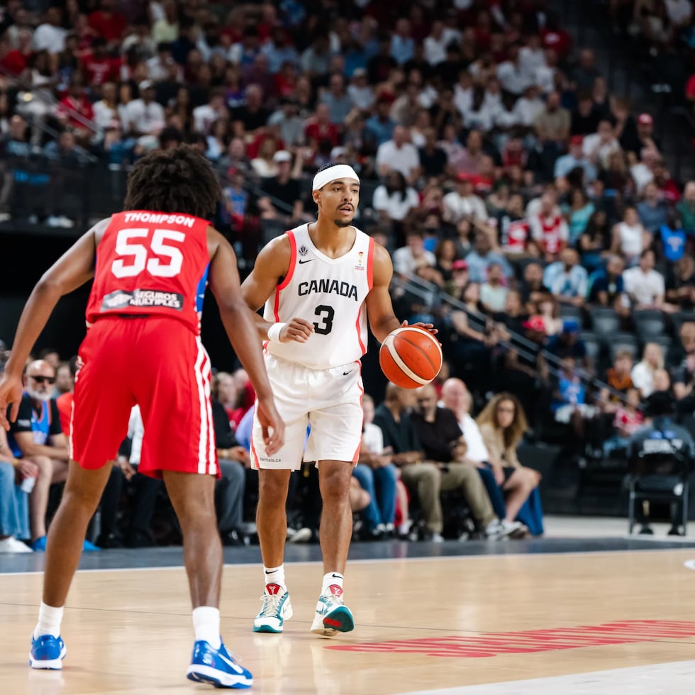 Andrew Nembhard, de Canadá, maneja el balón contra Ethan Thompson, de Puerto Rico.