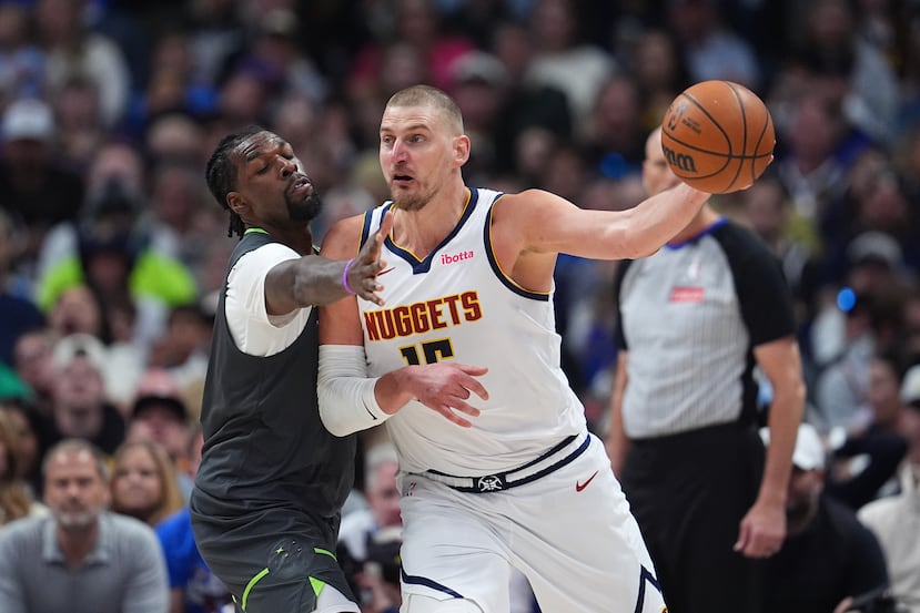Nikola Jokic, pívot de los Denver Nuggets (derecha), pasa el balón mientras Naz Reid, pívot de los Minnesota Timberwolves, lo defiende en la segunda mitad del primer partido de la primera ronda de los playoffs de la NBA, el sábado 18 de abril de 2026, en Denver. (Foto AP/David Zalubowski)