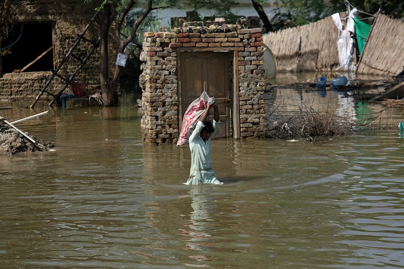 ARCHIVO - Un hombre transporta pertenencias rescatadas de su casa inundada por una zona inundada en el distrito de Shikarpur, provincia de Sindh, Pakistán, el miércoles 31 de agosto de 2022. (Foto AP/Fareed Khan, Archivo)