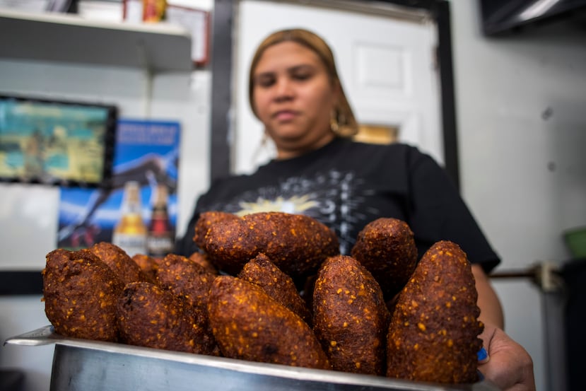 Aracelis Maisonet, empleada de "Aquí me quedo", saca de la cocina un apetitoso cargamento de alcapurrias.