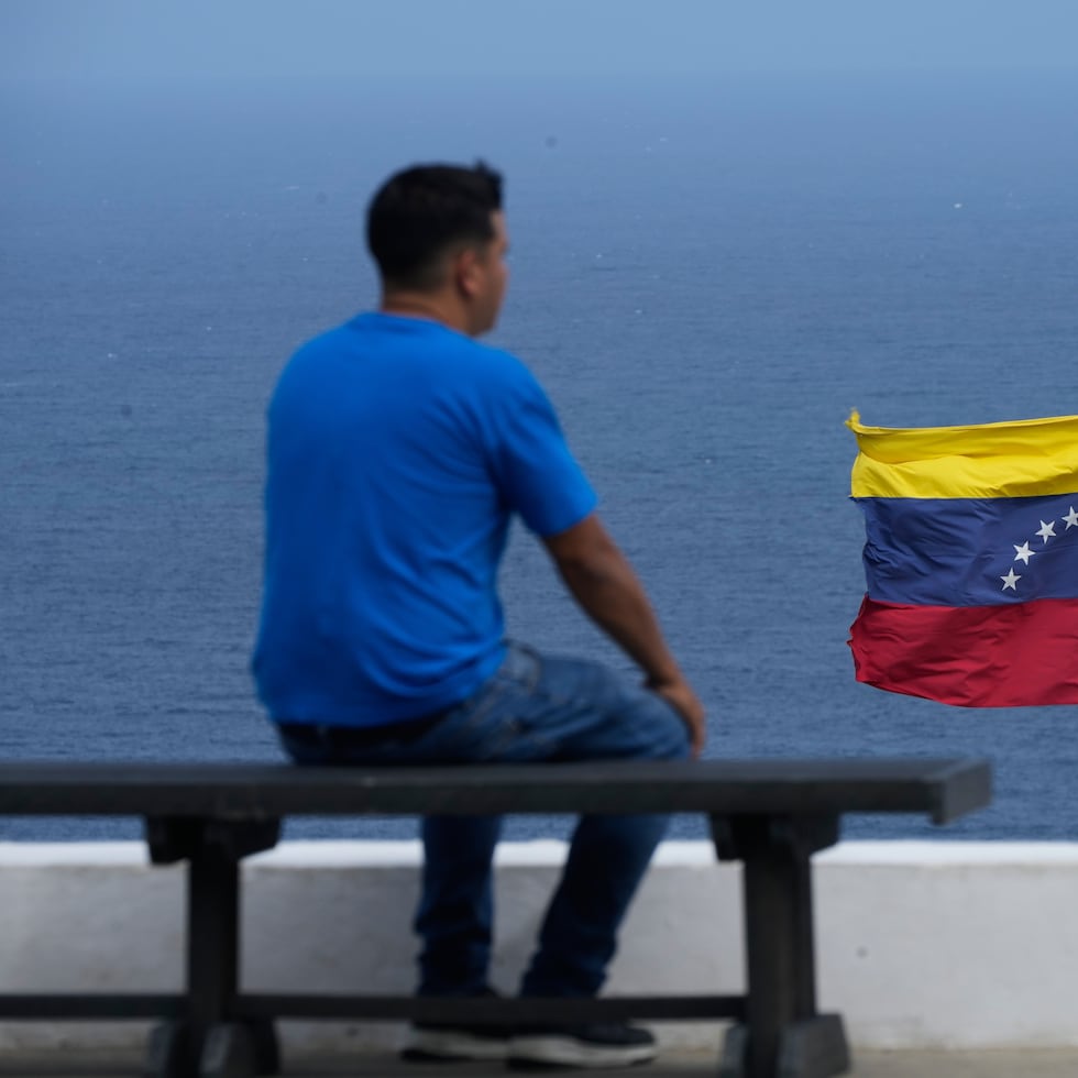 Un hombre mira el mar en la ciudad de La Guaira, Venezuela, donde ondea la bandera nacional.
