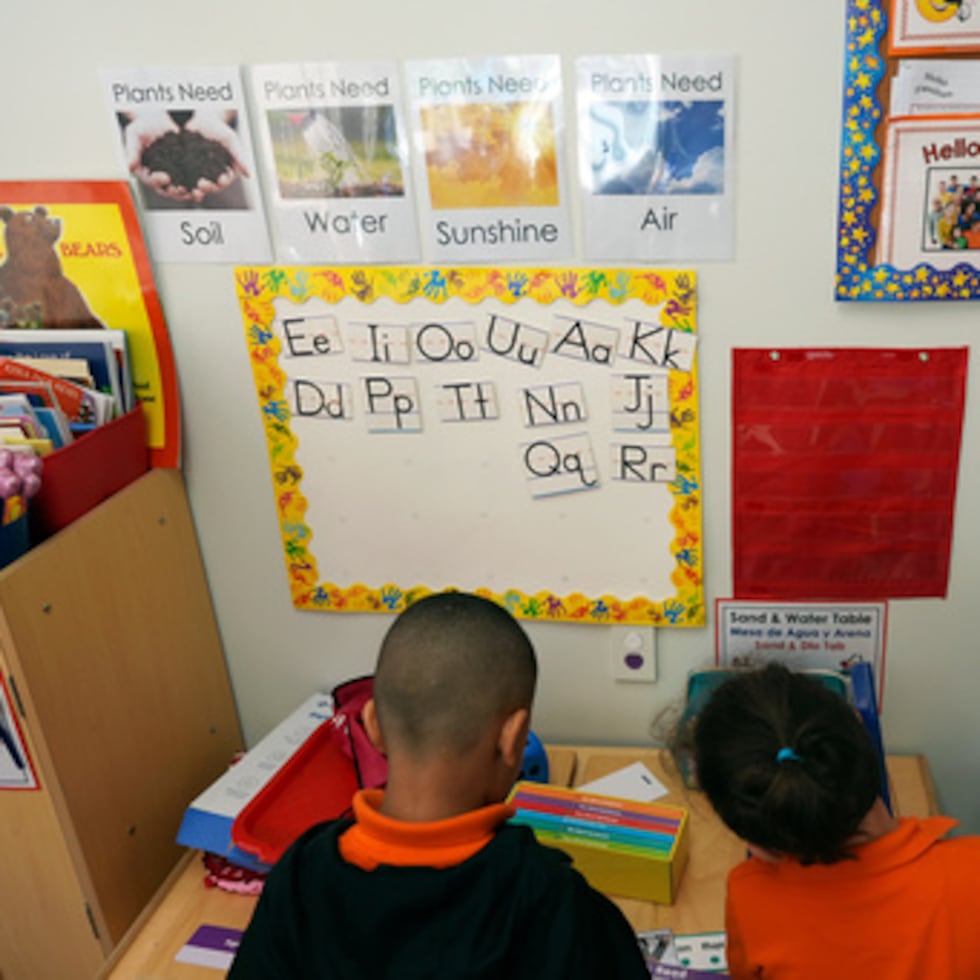 Unos alumnos ayudan a guardar el material al finalizar una clase de lectura y escritura en el programa Head Start.