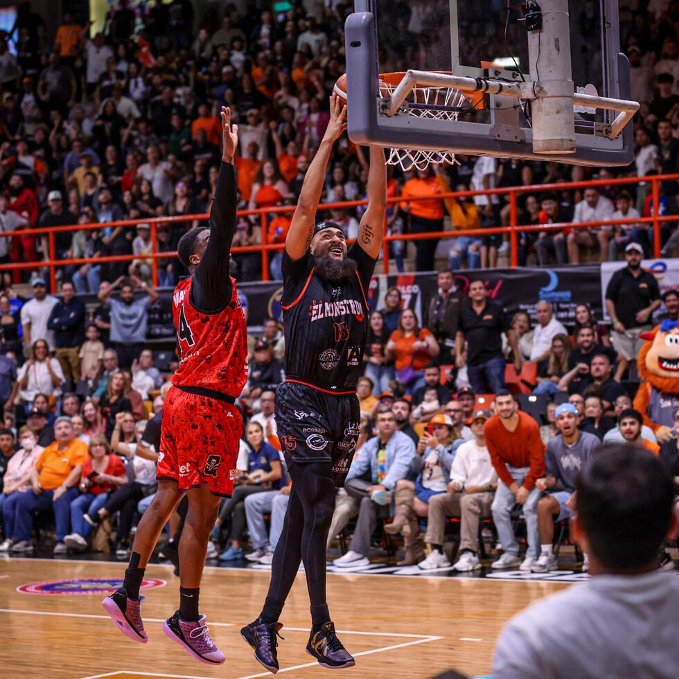 Onzie Branch, de los Atléticos de San Germán, se eleva hacia el canasto para anotar dejando atrás a Emmanuel Mudiay, de los Piratas de Quebradillas.