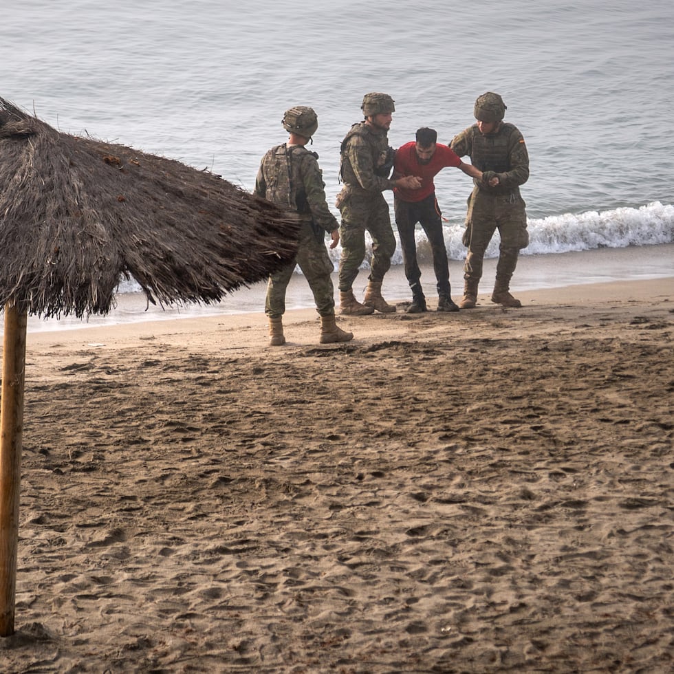 Soldados del ejército español ayudan a una persona que llegó a nado al enclave español de Ceuta, en el norte de África, desde Marruecos.