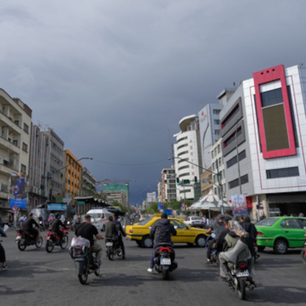 Motos y coches cruzan un cruce en el centro de Teherán, Irán.