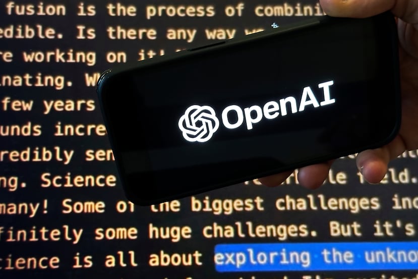 El logo de OpenAI en un teléfono celular frente a una pantalla que muestra el website de la compañía, en Nueva York el 21 de noviembre del 2023.